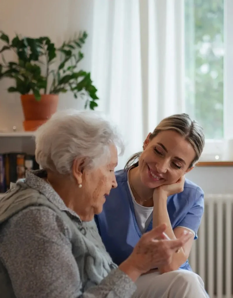 Caregiver listening warmly to an older woman in a bright, comfortable room